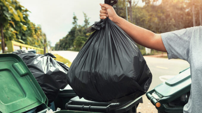 woman hand holding garbage in black bag for cleaning in to trash